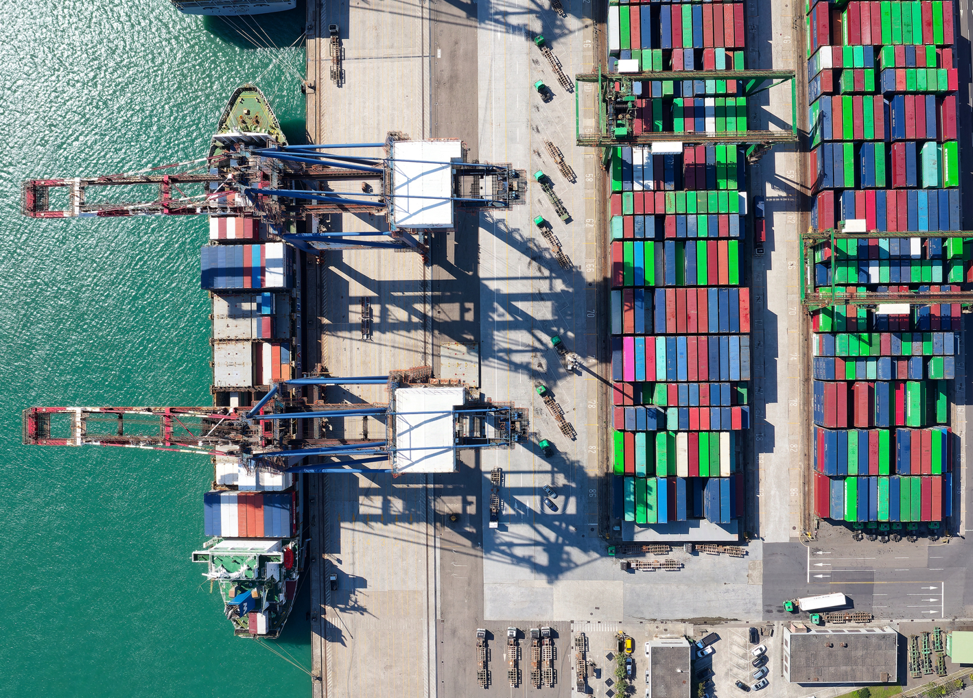 Overhead view of shipping containers and ship at a port facility.