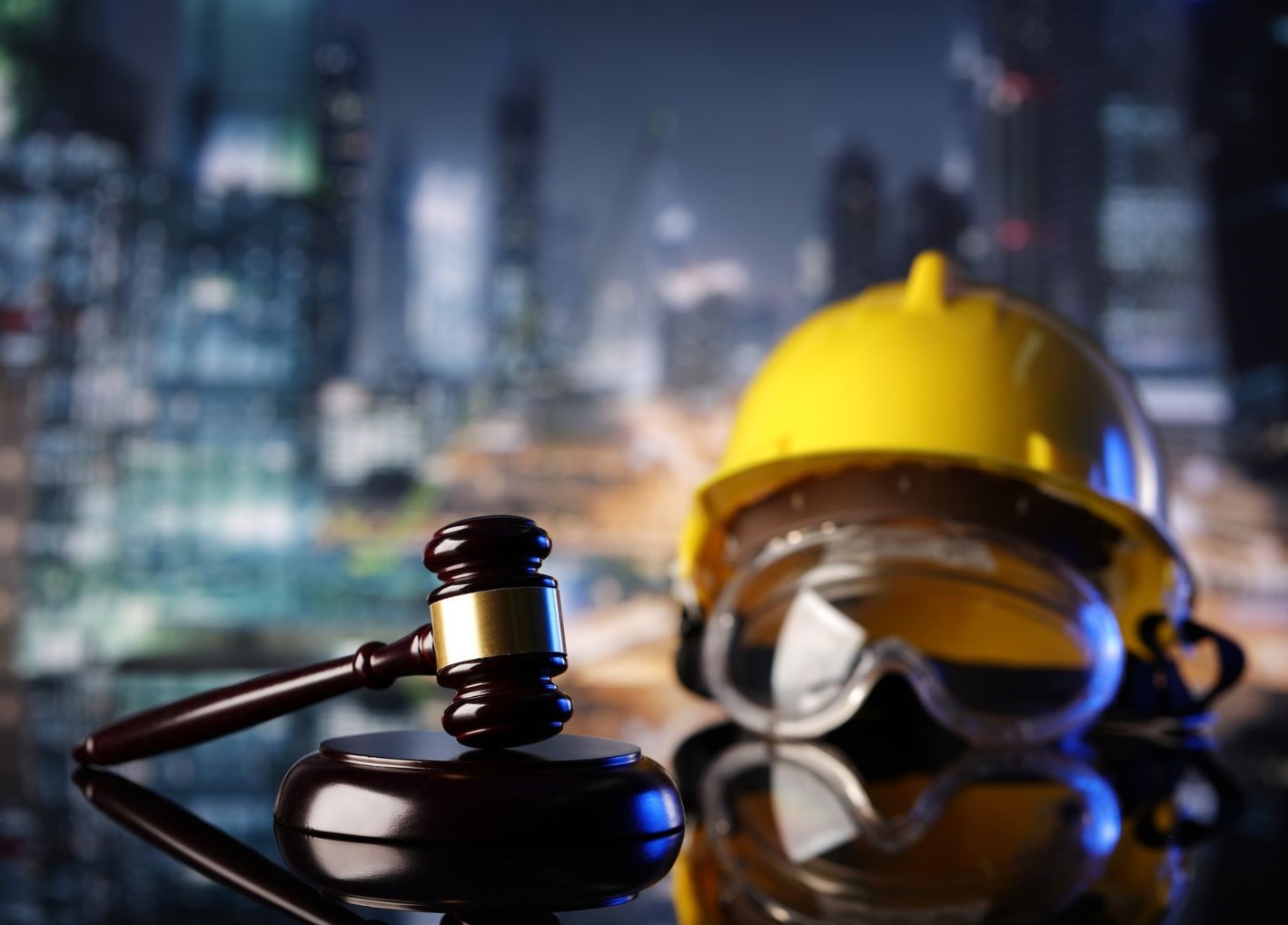 Gavel on a desk alongside construction helmet and goggles
