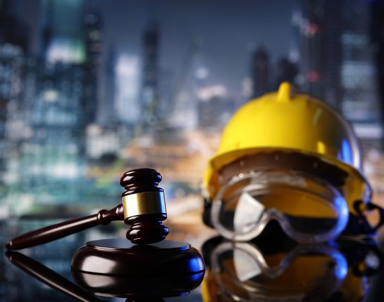 Gavel on a desk alongside construction helmet and goggles