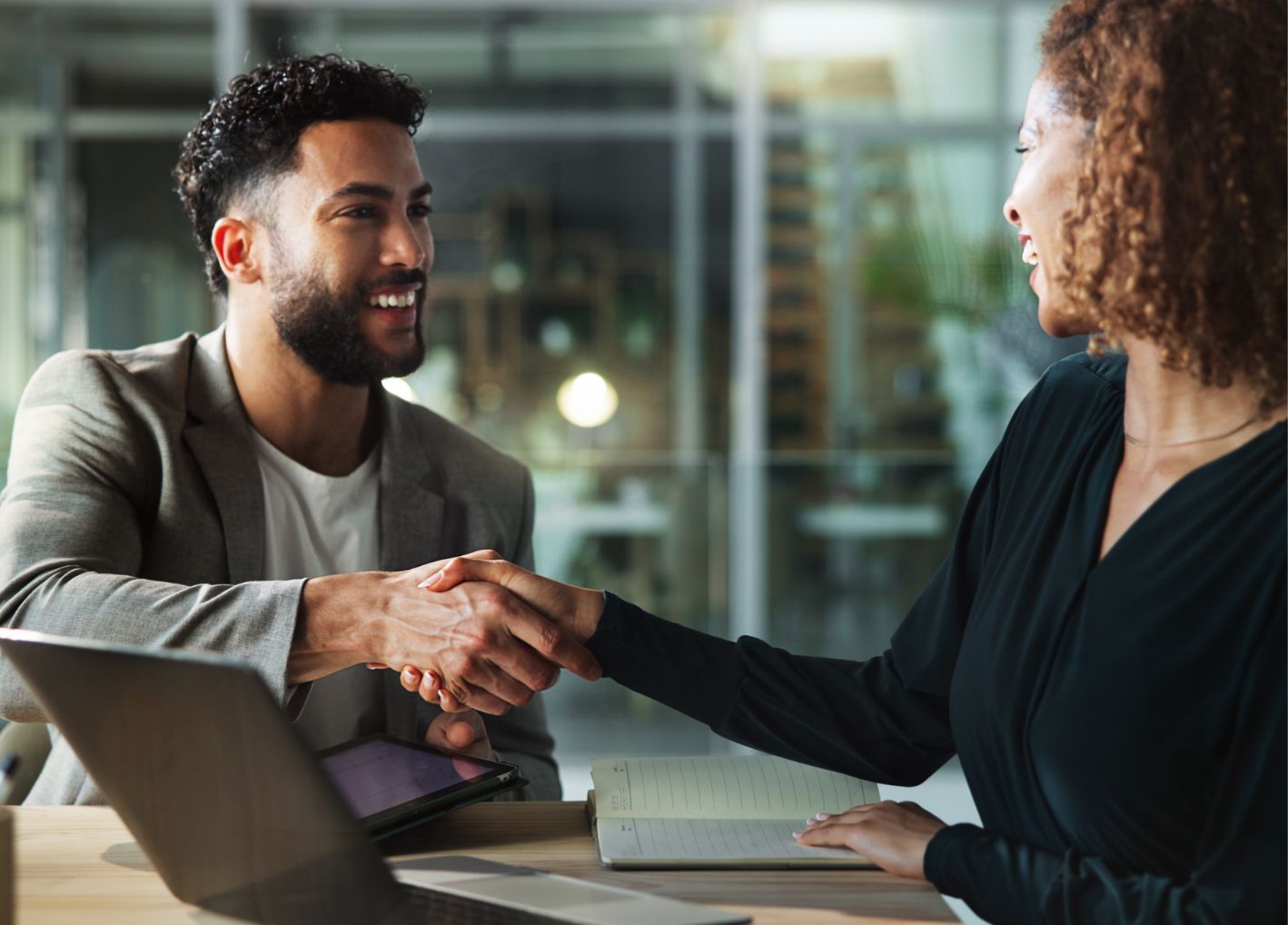 A man and woman shaking hands at a conference table