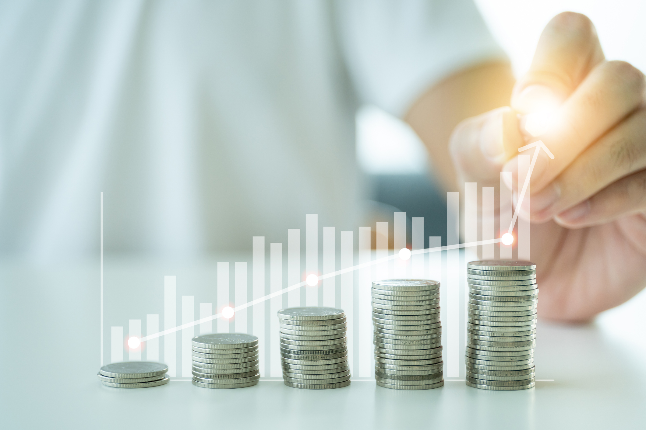 Stacks of coins increasing in size in the foreground of a growth chart