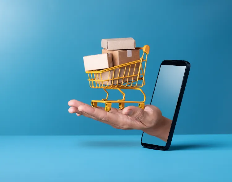 Mini shopping cart with cardboard boxes on hand through smartphone on blue background