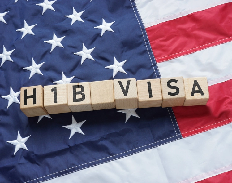 H-1B visa spelled out in wooden blocks over an American flag.