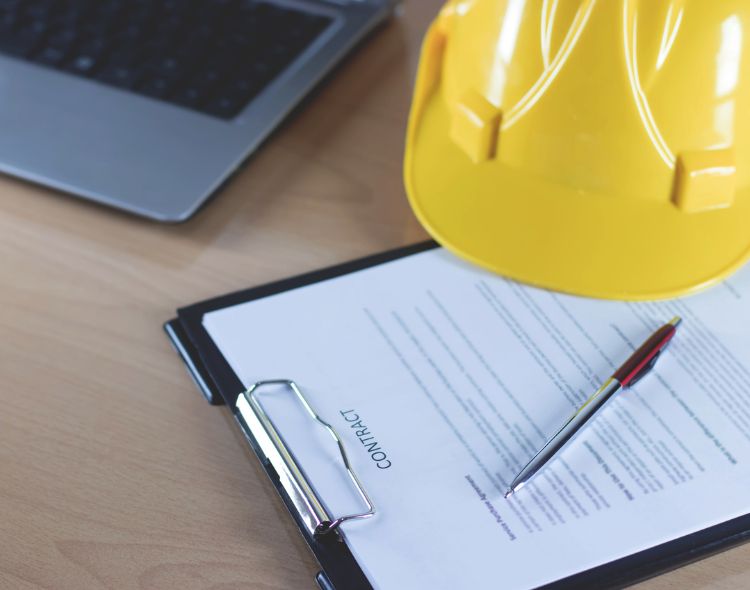 Contract on clipboard with pen and hard hat