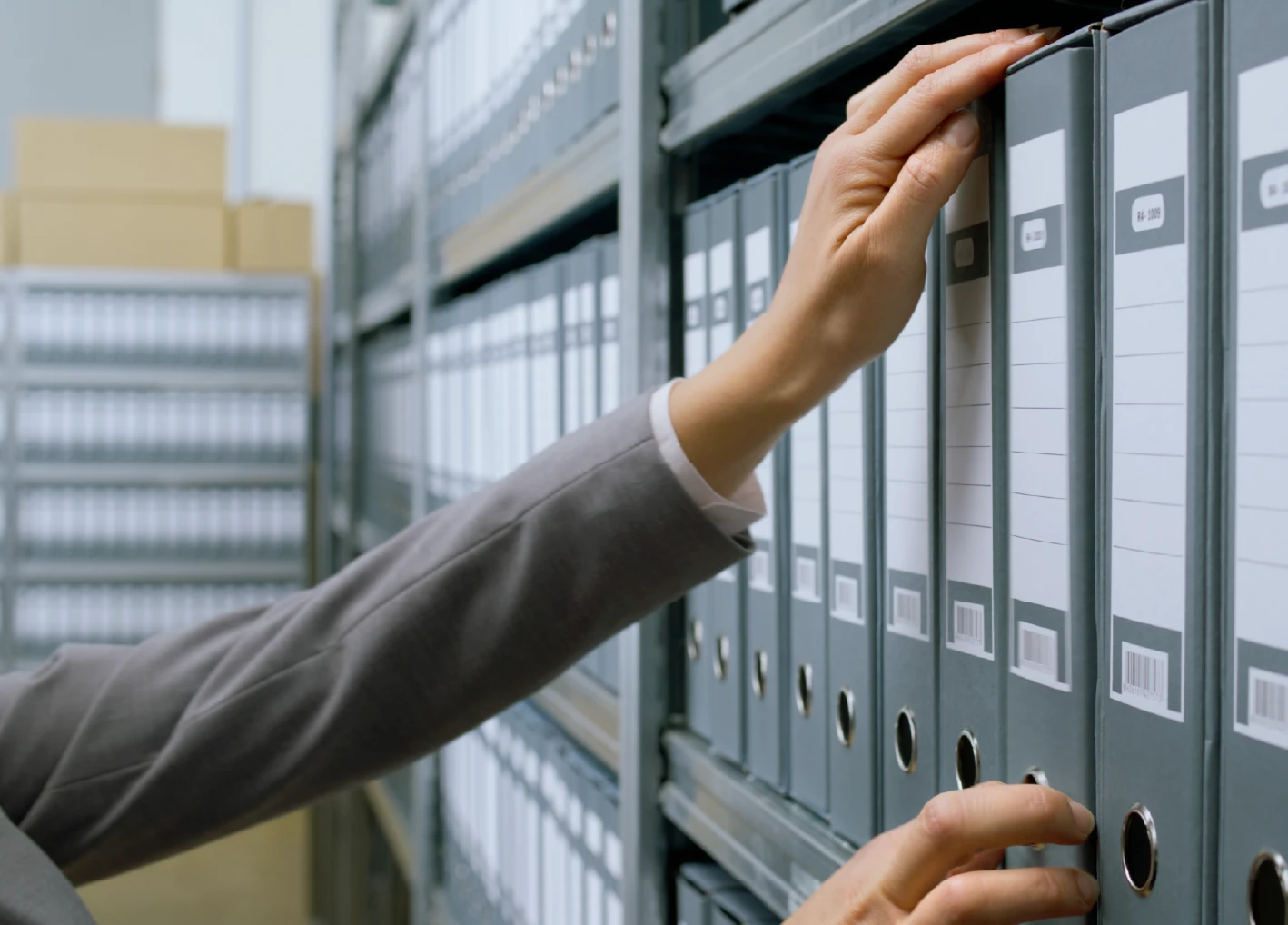 Archivist Hand Choosing File from Archive Binder Shelf